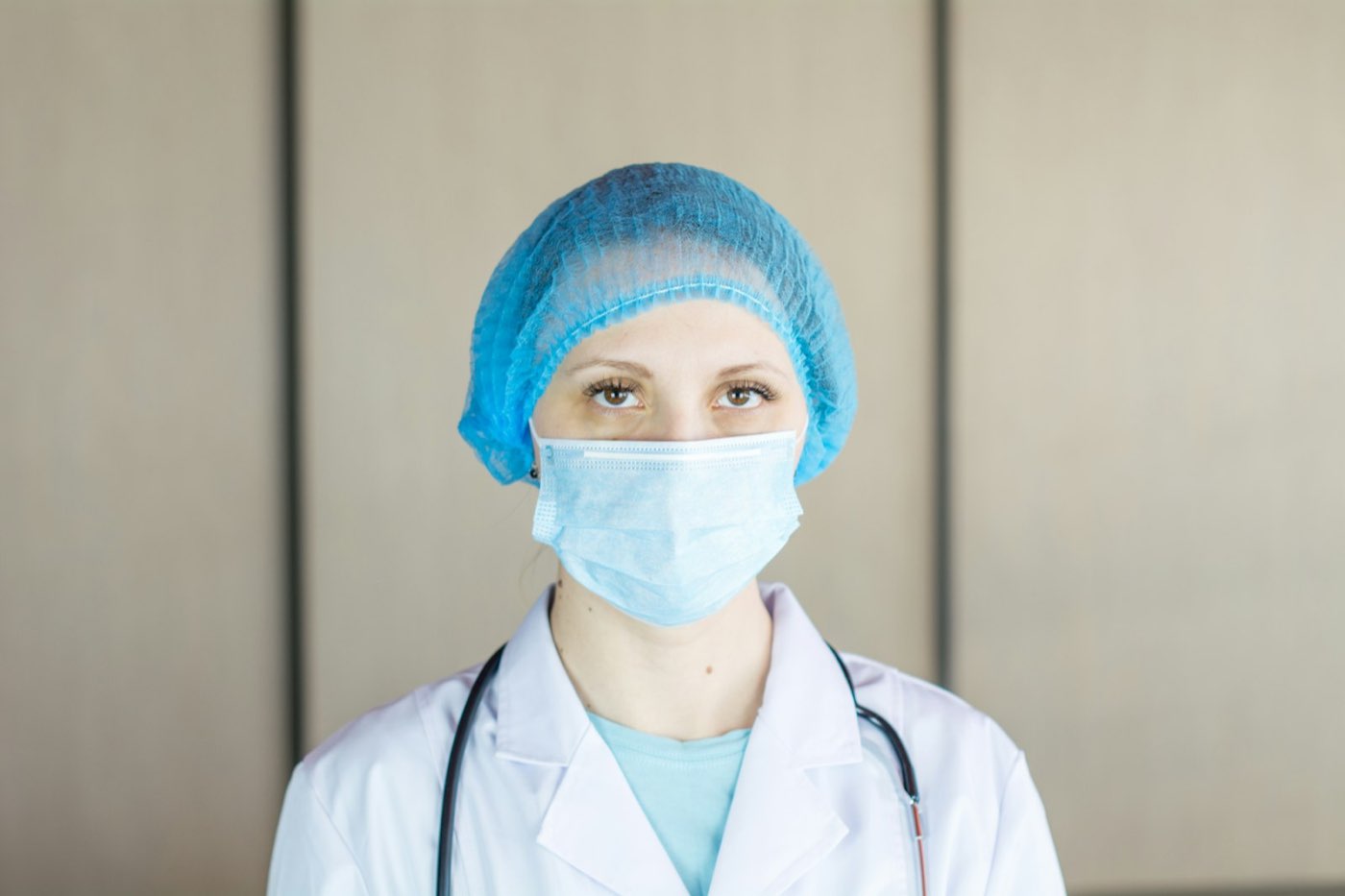 A clinician wearing a face mask and protective cap